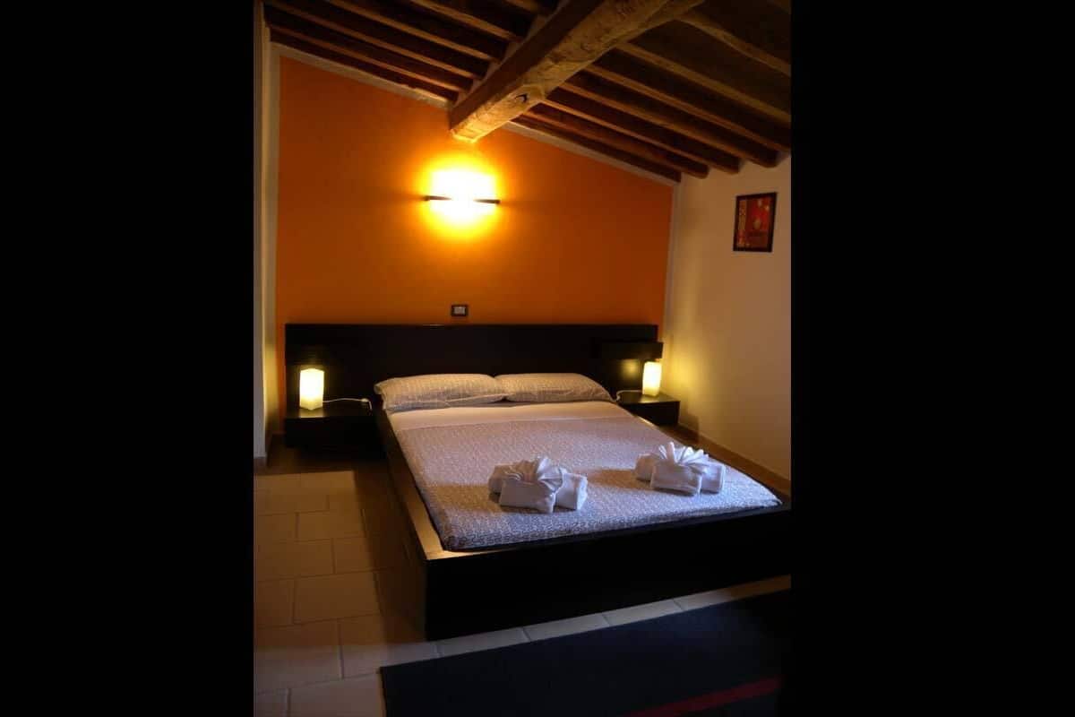 Een hotelkamer met een bed, nachtkastjes en een wandlamp.