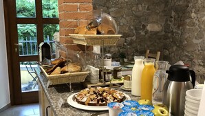 A breakfast buffet with bread, pastries, and beverages.