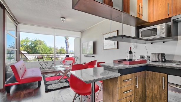 A modern kitchen with a built-in microwave, a wine bottle, and a toaster. - Red Velvet  Apartment (Santiago)