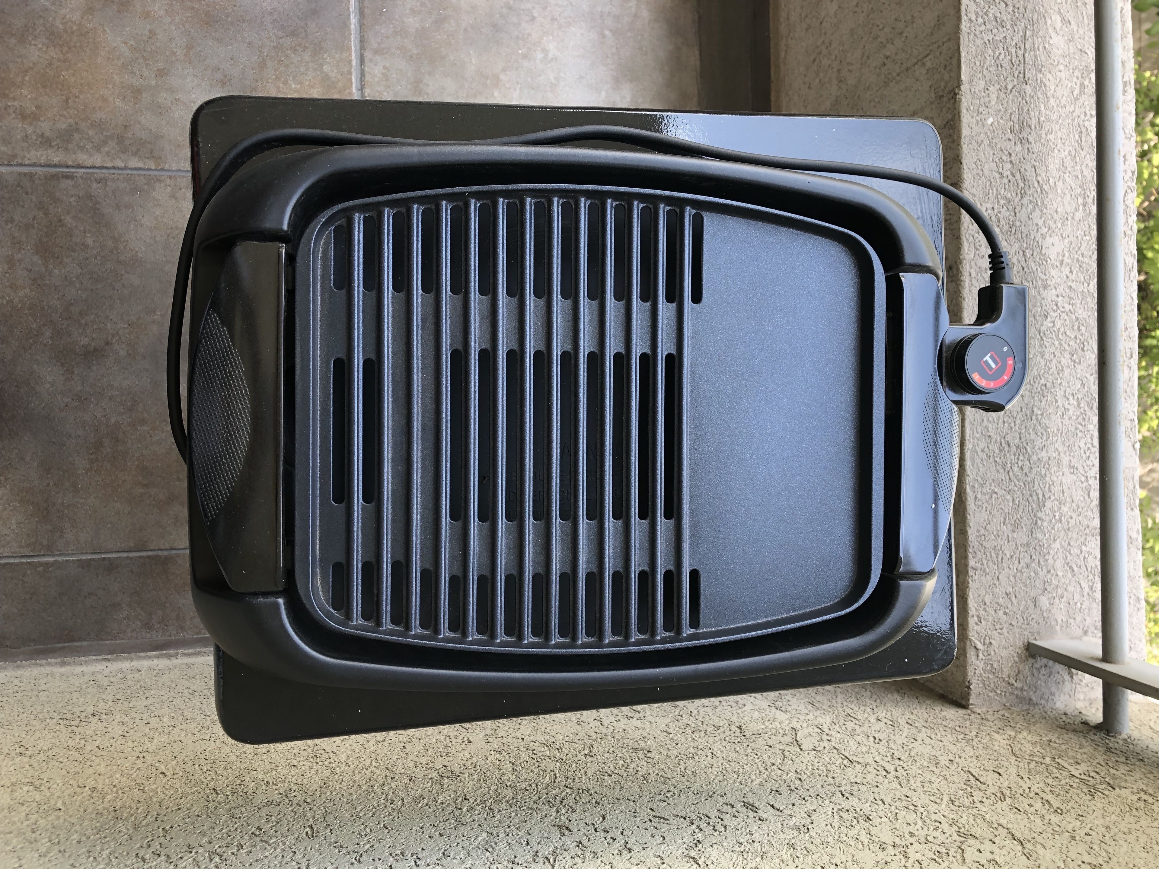 A black portable heater with a control knob, mounted on a wall.