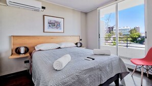 A modern hotel room with a large bed, a view of the city, and a balcony. - Red Velvet  Apartment (Santiago)