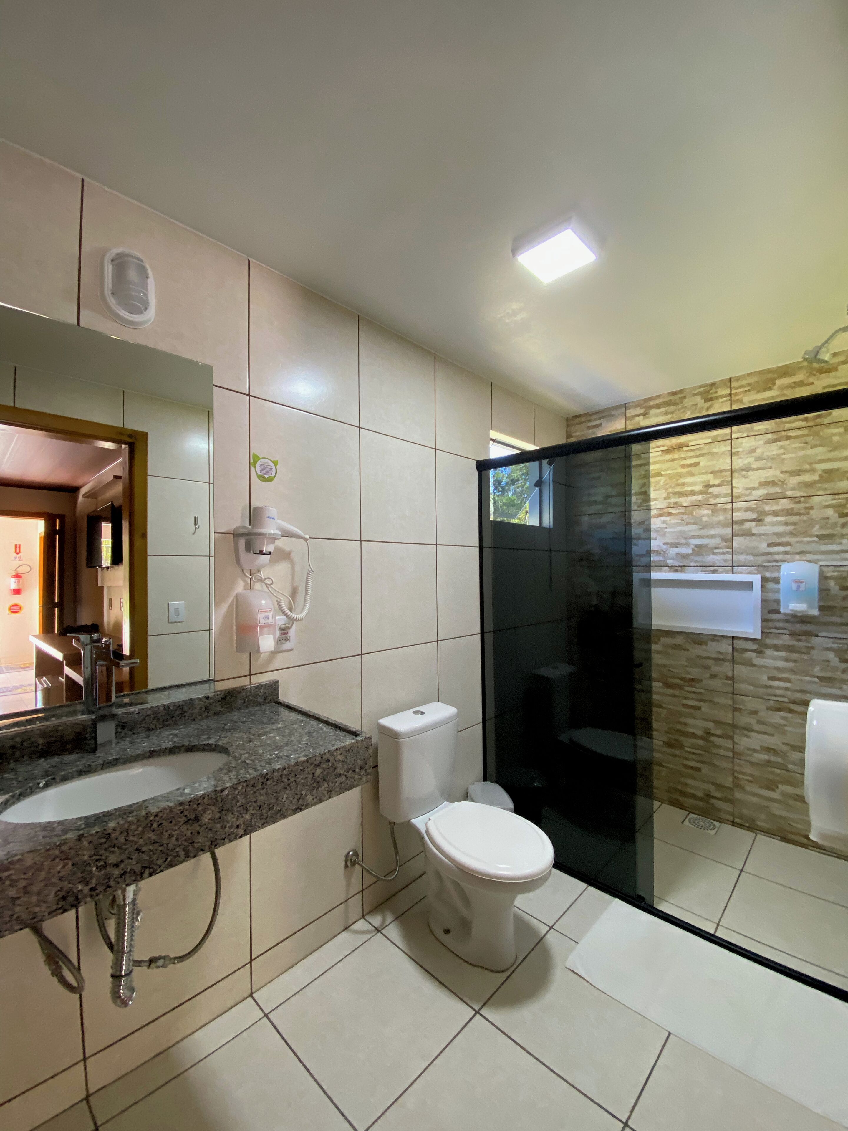 Un baño moderno con encimera de granito, inodoro y ducha con mampara de vidrio.