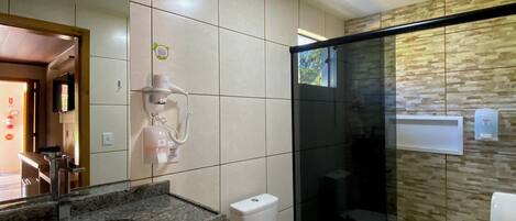 A modern bathroom with a granite countertop, a toilet, and a glass-enclosed shower.