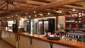 Een bar met houten balken, flessenkasten en een gekoelde vitrine.