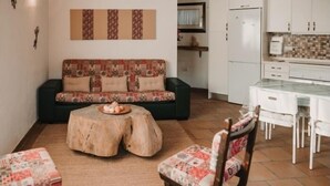 Un salón acogedor con un sofá estampado, una mesa redonda de madera y dos sillones tapizados con motivos florales.