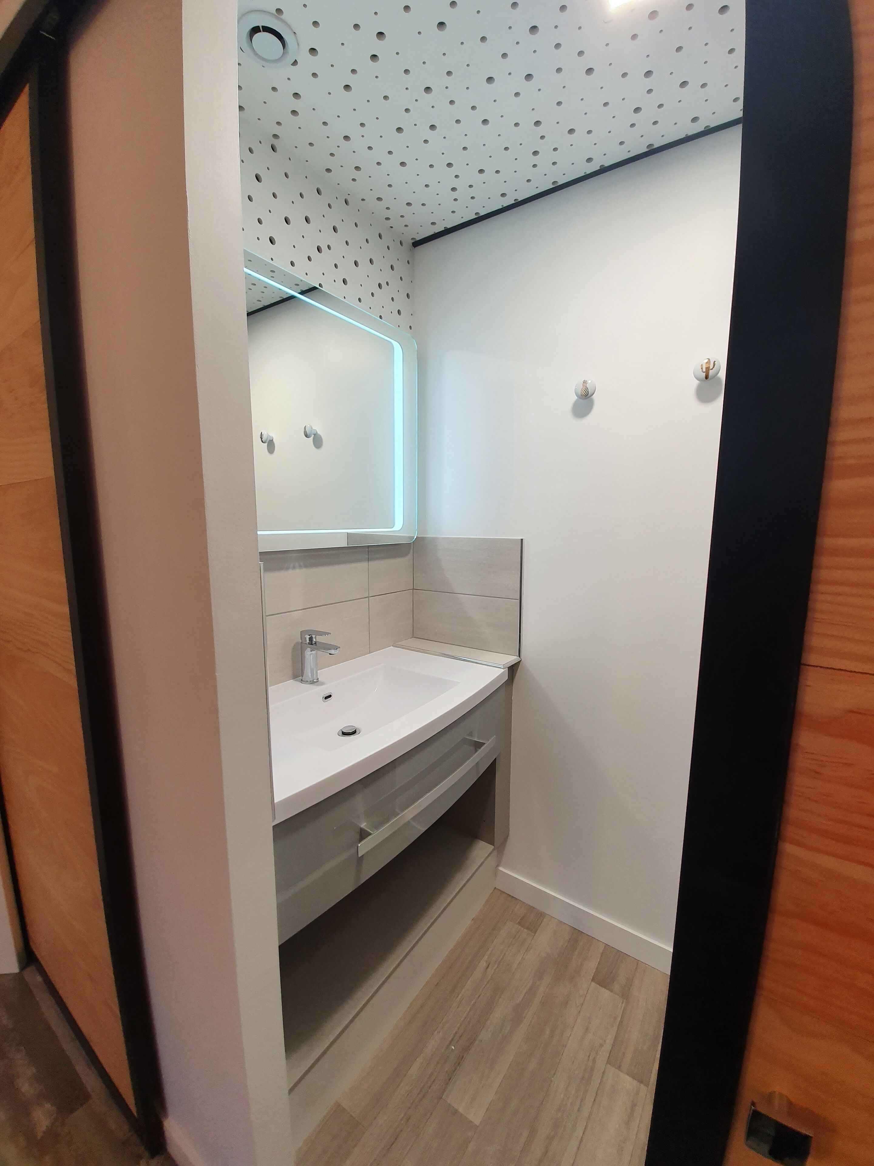 Un baño moderno con un lavamanos blanco, un espejo y una ducha.