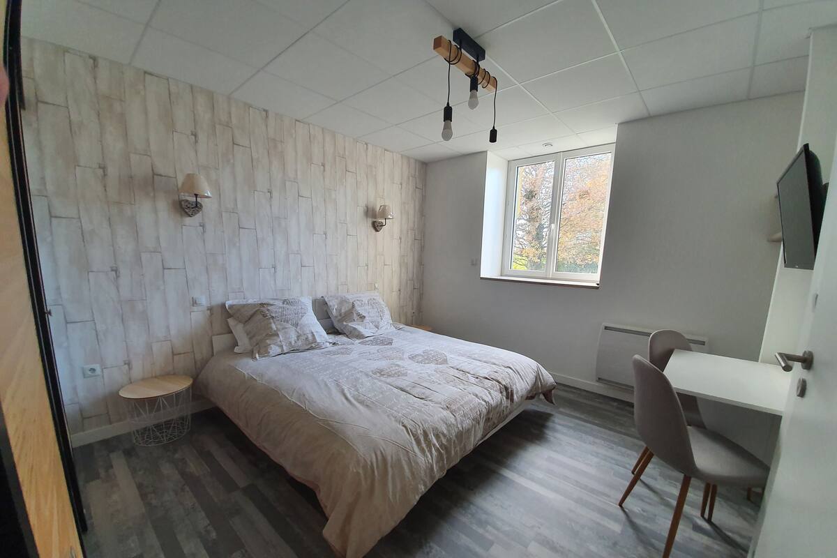 Um quarto com uma cama, uma escrivaninha e uma cadeira.
