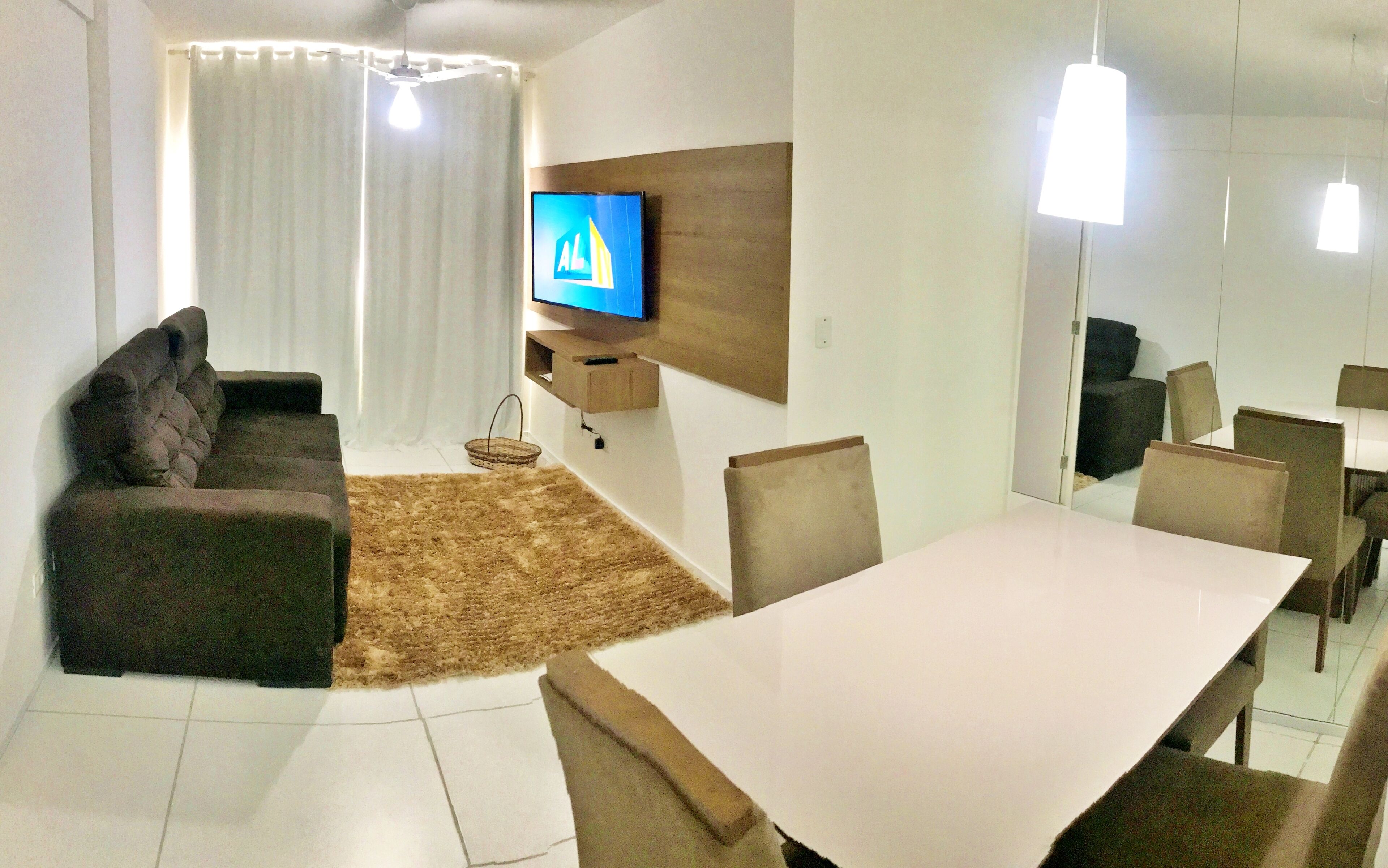 Una sala moderna con un televisor de pantalla plana, un sofá, una mesa de comedor y sillas.