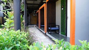 Un pasillo con bancos, una puerta con letrero de número y una pared verde.