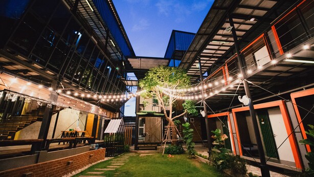 Un patio con césped, un árbol y un banco de madera.