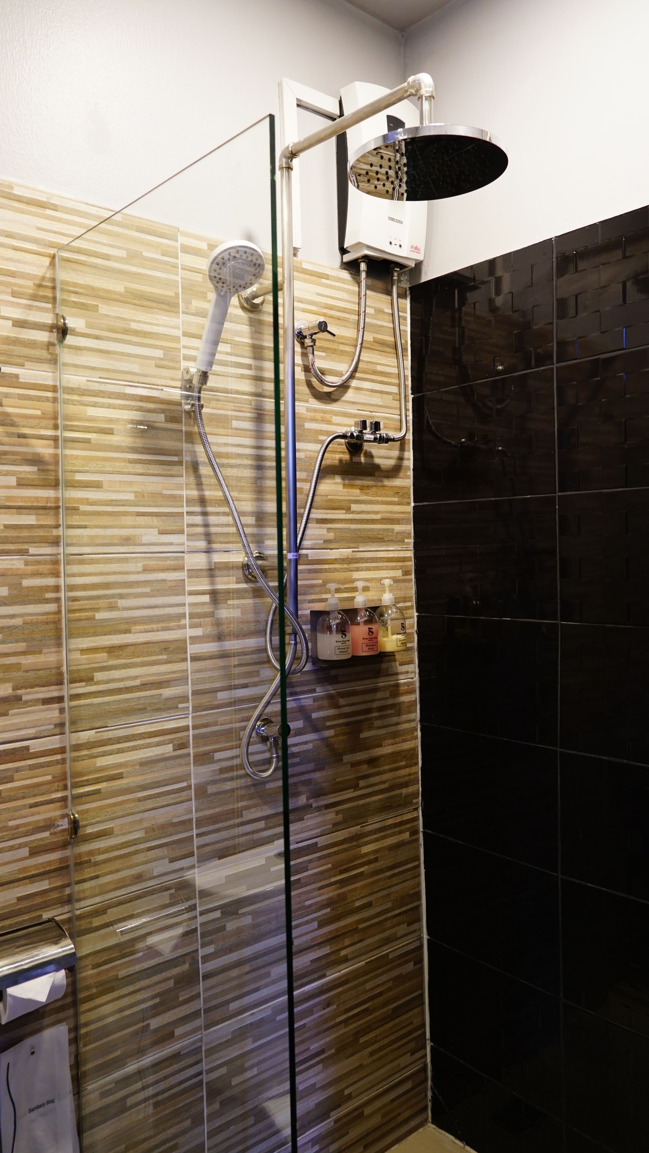 A shower with a rain showerhead, a handheld showerhead, and a handheld shower attachment.