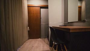 Una habitación con un escritorio de madera, una silla, un espejo y una puerta.