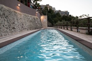 Una piscina con un muro de piedra en un lado y una valla de madera en el otro.