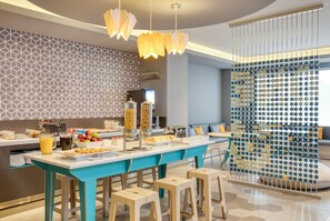 A modern kitchen with a central island, bar stools, and a decorative partition.