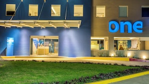 A hotel exterior with a prominent 'one' sign, a glass entrance, and a well-lit facade.