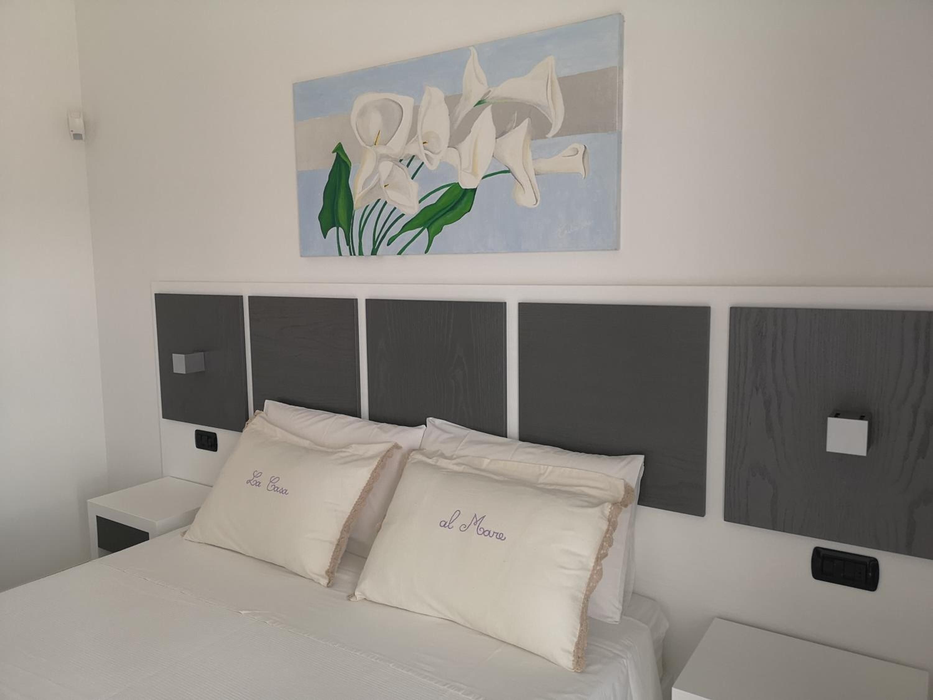 Un dormitorio con una cama, dos mesitas de noche, una obra de arte en la pared y un cabecero con diseño de panel.