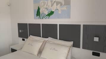 Un dormitorio con una cama, dos mesitas de noche, una obra de arte en la pared y un cabecero con diseño de panel.