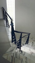 Una escalera con piso de mármol y barandilla de metal.