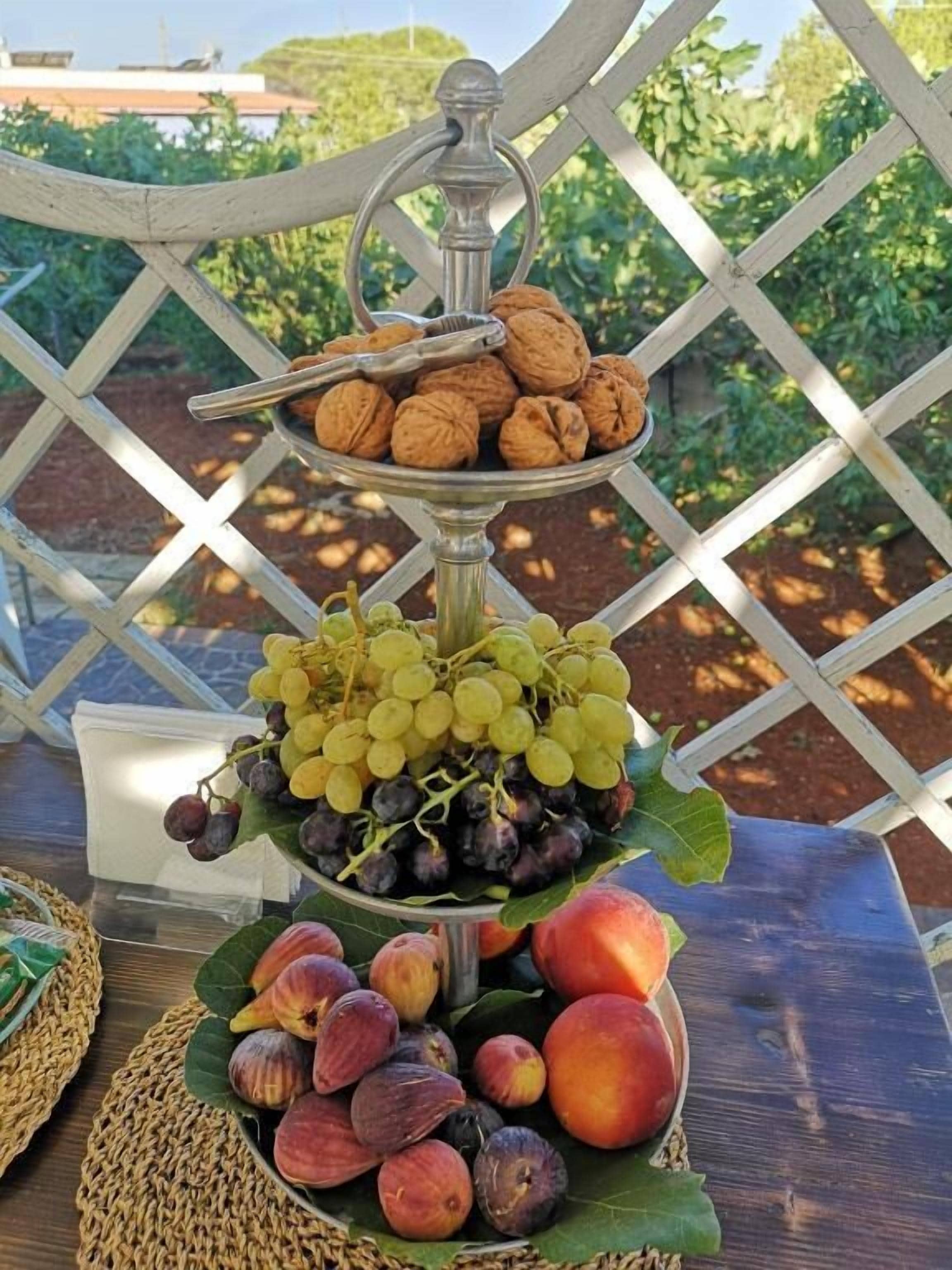A tiered fruit and nut display on a table with a lattice backdrop.
