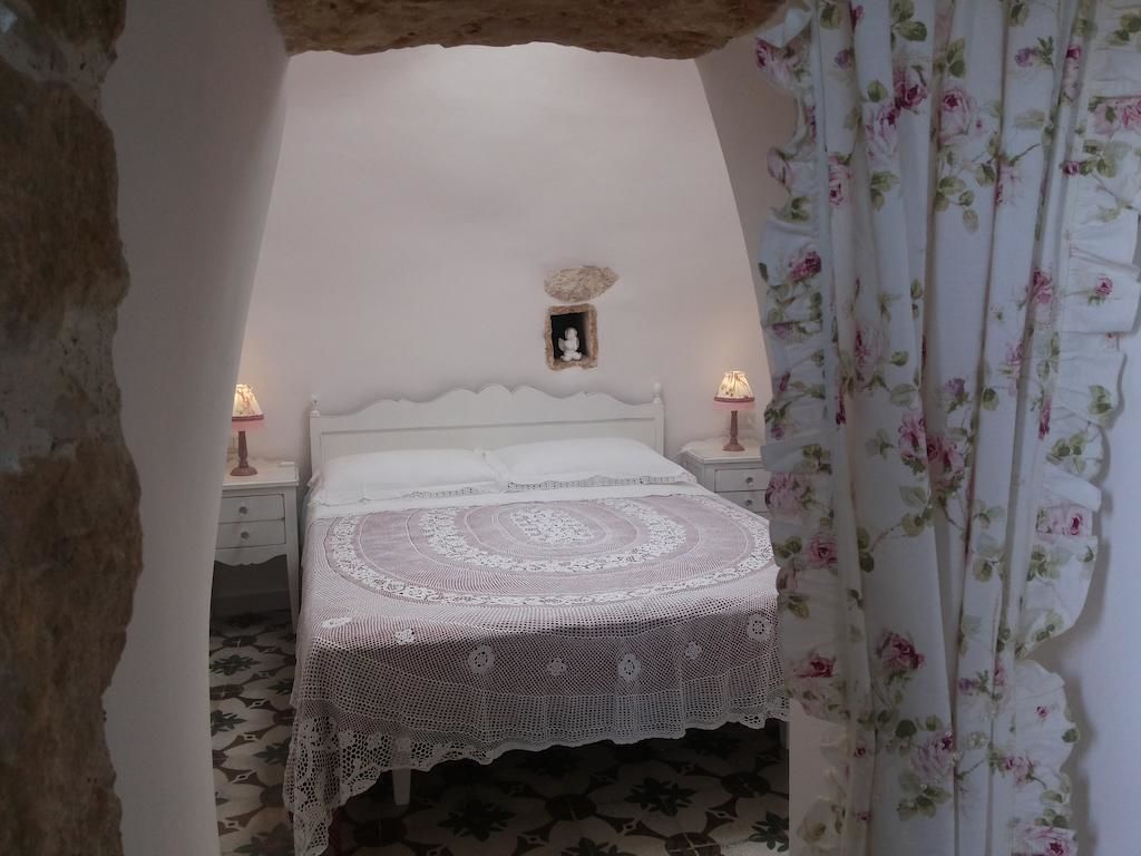 A bedroom with a bed, a nightstand, a wall-mounted shelf, and a floral curtain.