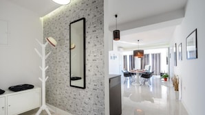 A modern interior with a white coat rack, a large mirror, and a dining area with a chandelier.