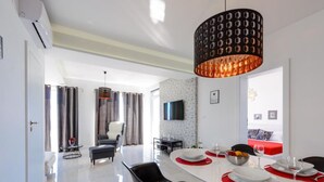 A modern dining area with a white table, black chairs, and a unique pendant light.