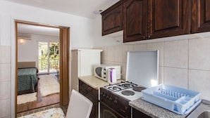 Una cocina compacta con armarios de madera, cocina a gas, microondas y refrigerador.