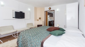 Una habitación de hotel moderna con una cama, un televisor montado en la pared, una mesita y un rincón de descanso.