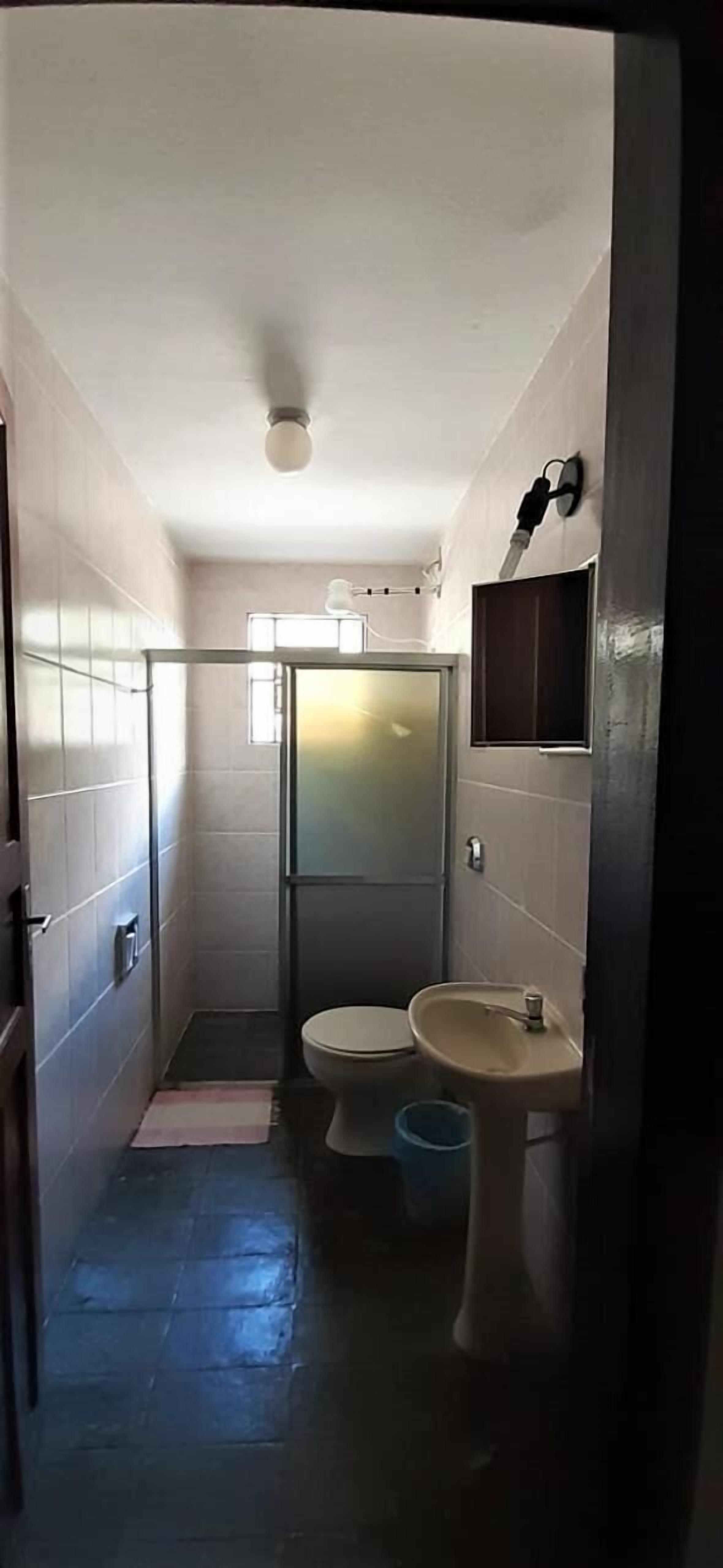 Casa de banho compacta com sanita, lavatório e chuveiro.