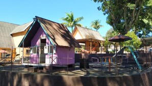 Un parque infantil con una casita de juegos rosa, un tobogán y columpios.