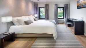Quarto moderno com uma cama grande, uma escrivaninha e vista para o verde lá fora.