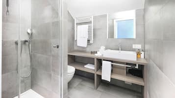 A modern bathroom with a glass-enclosed shower, a white sink, and a large mirror.