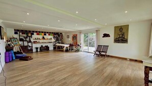 A spacious room with wooden flooring, a large window, and a Buddha statue on the wall.