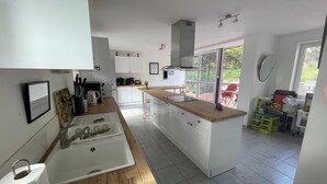 A modern kitchen with white cabinets, a wooden countertop, and a large window providing natural light.