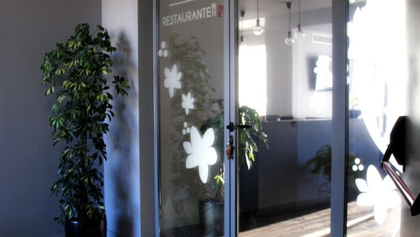 A reception area with a glass door, a potted plant, and a sign indicating a restaurant. - Basto Vila Hotel (Cabeceiras de Basto)