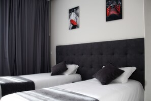 A hotel room with two beds, grey curtains, and two framed pictures on the wall. - Basto Vila Hotel (Cabeceiras de Basto)