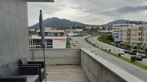 A balcony with outdoor furniture, a view of a road and buildings, and a mountain in the distance. - Basto Vila Hotel (Cabeceiras de Basto)