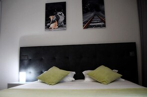 A bedroom with a large bed, two green pillows, a dark headboard, and two framed pictures on the wall. - Basto Vila Hotel (Cabeceiras de Basto)