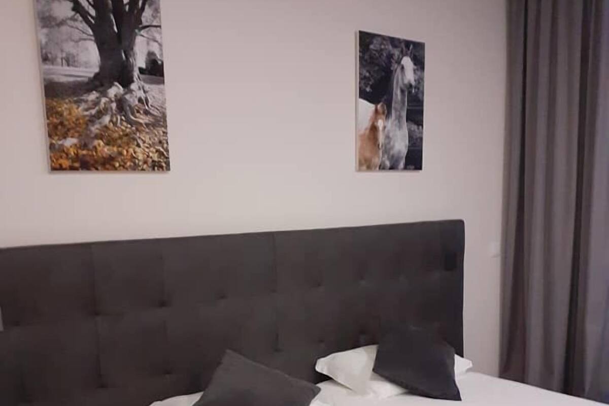 Habitación de hotel con una cama grande, dos almohadas, una mesita de noche y dos cuadros en la pared.