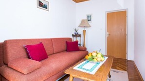 A living room with a sofa, a wooden coffee table with fruit, a lamp, and a door.