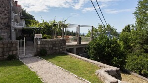 A stone building with a covered outdoor seating area and a view of the sea.