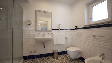 A bathroom with a glass shower enclosure, a sink, a toilet, and a mirror.