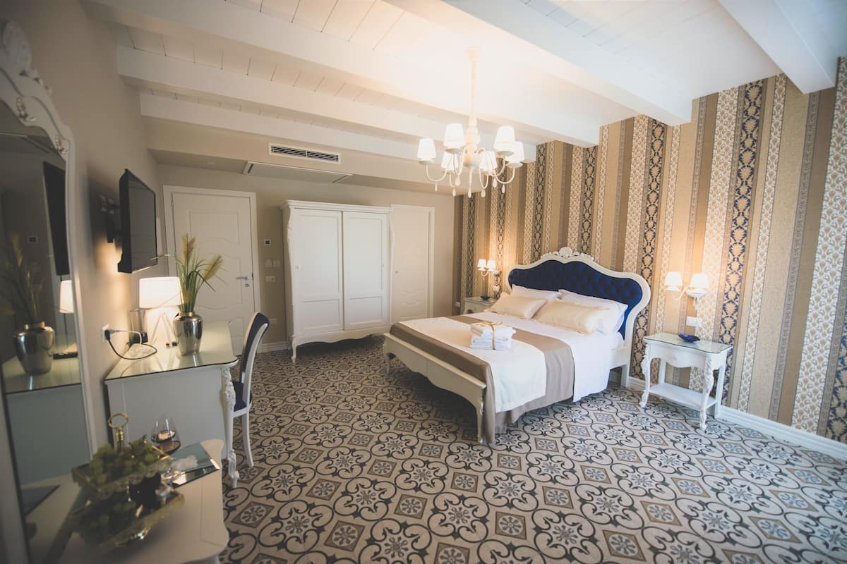Una camera d'albergo con un letto, un comodino, una lampada e uno specchio.