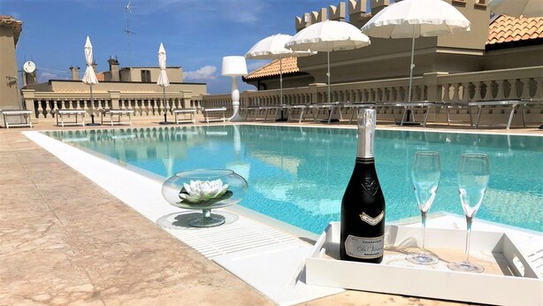 A poolside area with a champagne bottle and glasses, a lotus flower decoration, and lounge chairs. - Sui Generis (Tropea)