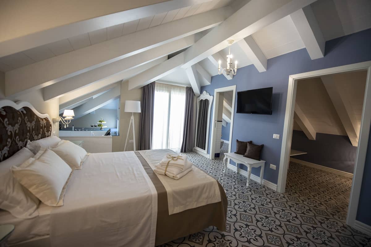Una camera da letto con un letto grande, una TV fissata al muro e un lampadario.