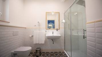 Een moderne badkamer met toilet, wastafel en douche met glazen wanden.