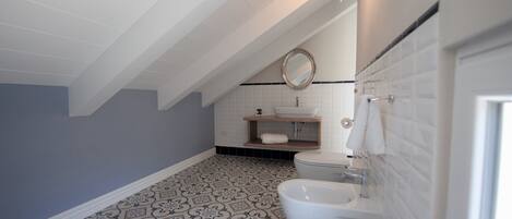 A bathroom with a patterned floor, a toilet, a sink, and a mirror.