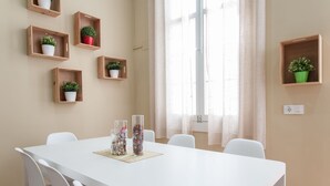 Ein Essbereich mit einem weißen Tisch, weißen Stühlen und Holzregalen mit Topfpflanzen.
