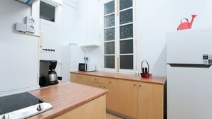 Eine kompakte Küche mit eingebautem Herd, einer Mikrowelle und einem Kühlschrank. Ein Fenster mit satiniertem Glas und eine kleine Spüle mit Armatur sind vorhanden.