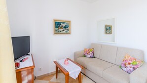 A living room with a sofa, a coffee table, a TV, and two framed artworks on the wall. - Apartments Nicol - Two-Bedroom Apartment with Balcony and Sea View (Dubrovnik)